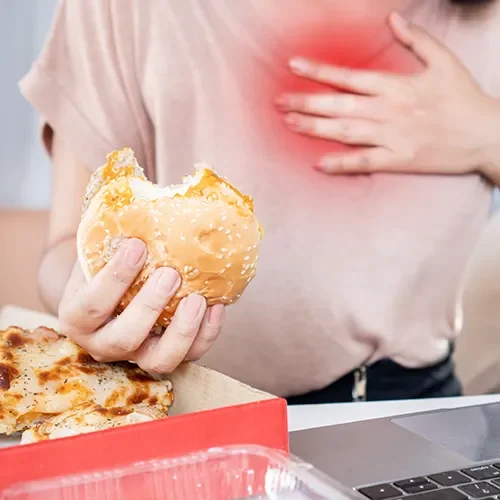 Jak wygląda dieta na zgagę? Co jeść i pić na zgagę, a czego unikać w jadłospisie? Kobieta ma zgagę po zjedzeniu pączka.