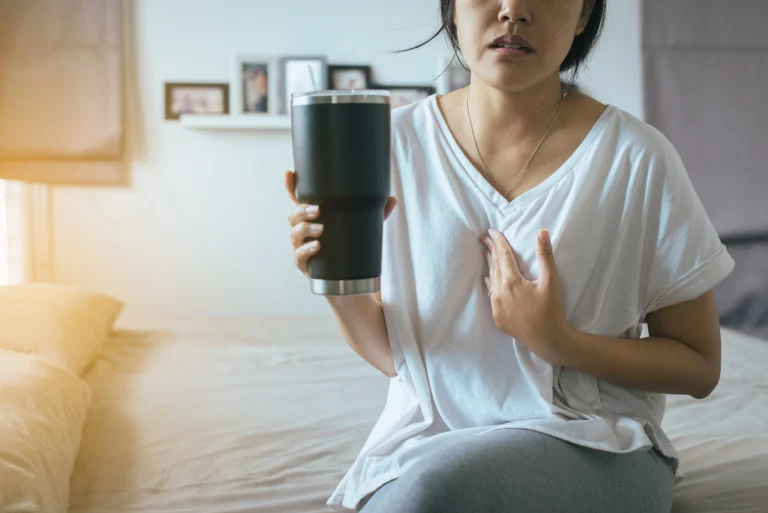 kobieta w białej koszulce trzyma bidon, ma grymas świadczący o zgadze lub bólu