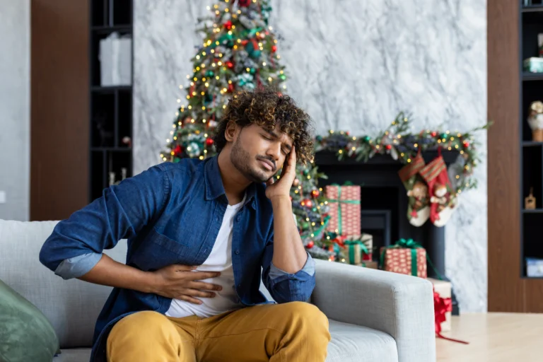 mężczyzna w niebieskiej koszuli i żółtych spodniach trzyma się za brzuch i głowę